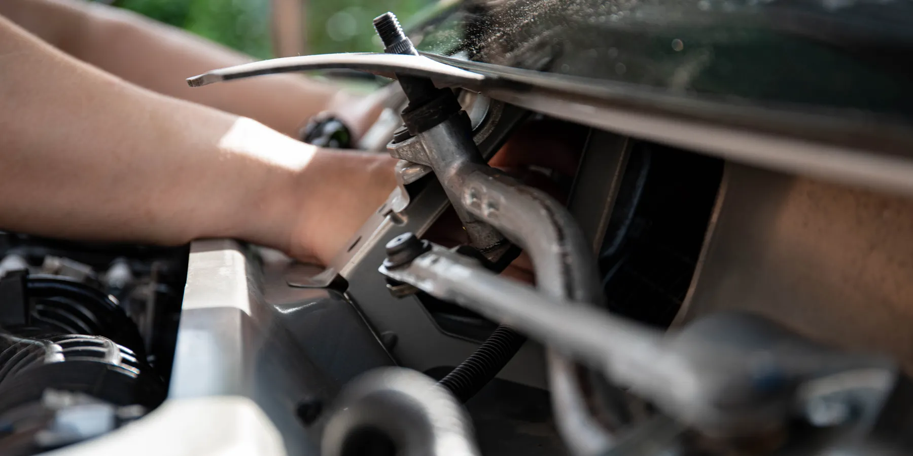 Hands checking components during an under-hood repair