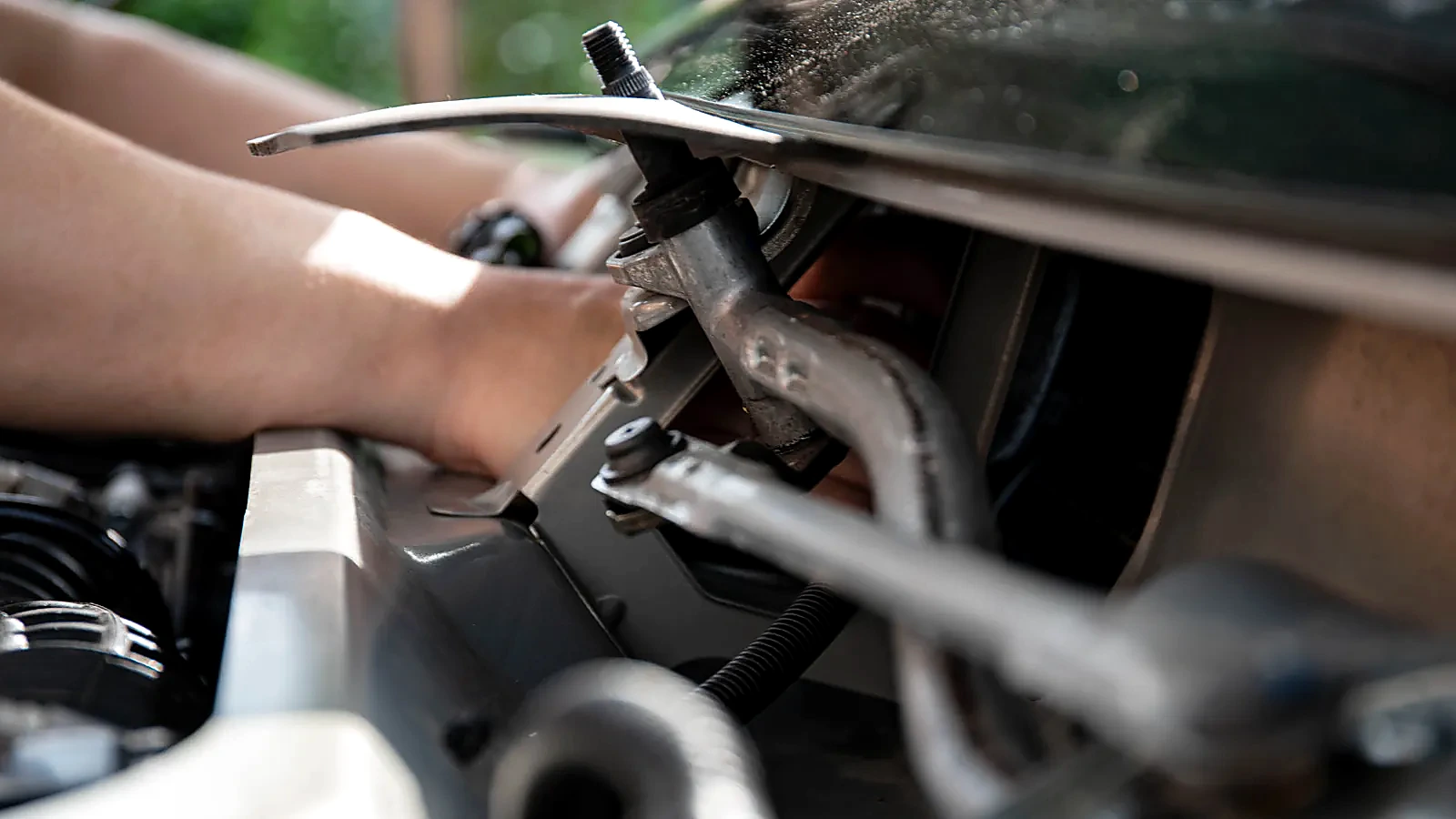 Technician hands working under the hood during repair