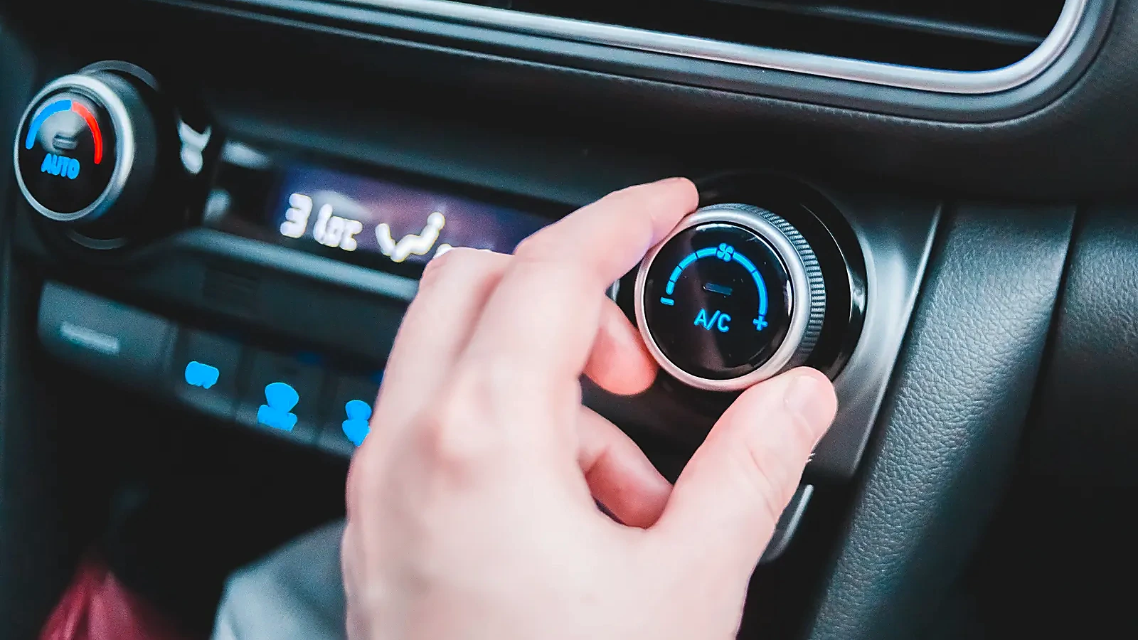 Hand adjusting the air-conditioning controls inside a vehicle